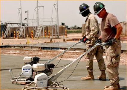 US Seabees using steel paving forms to finish concrete foundation work for a vehicle maintenance building